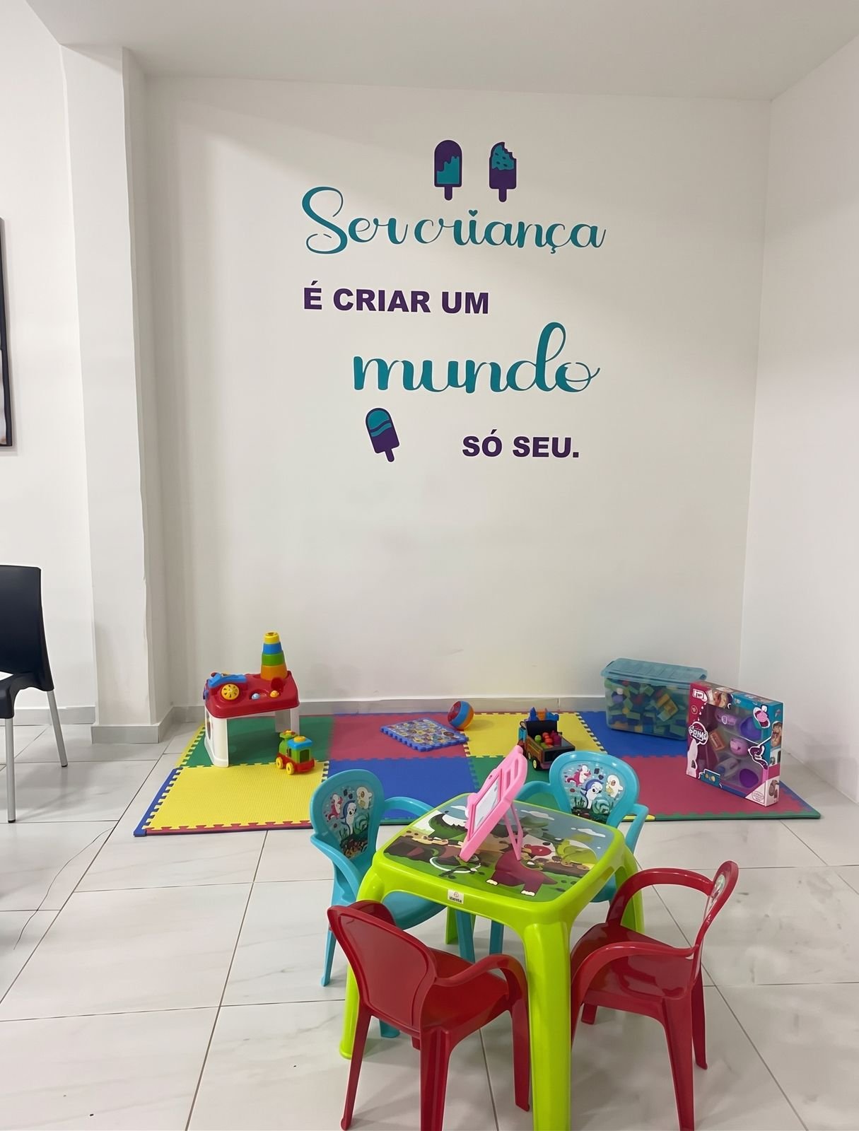 Brinquedoteca com tapete colorido, mesinha infantil e brinquedos
